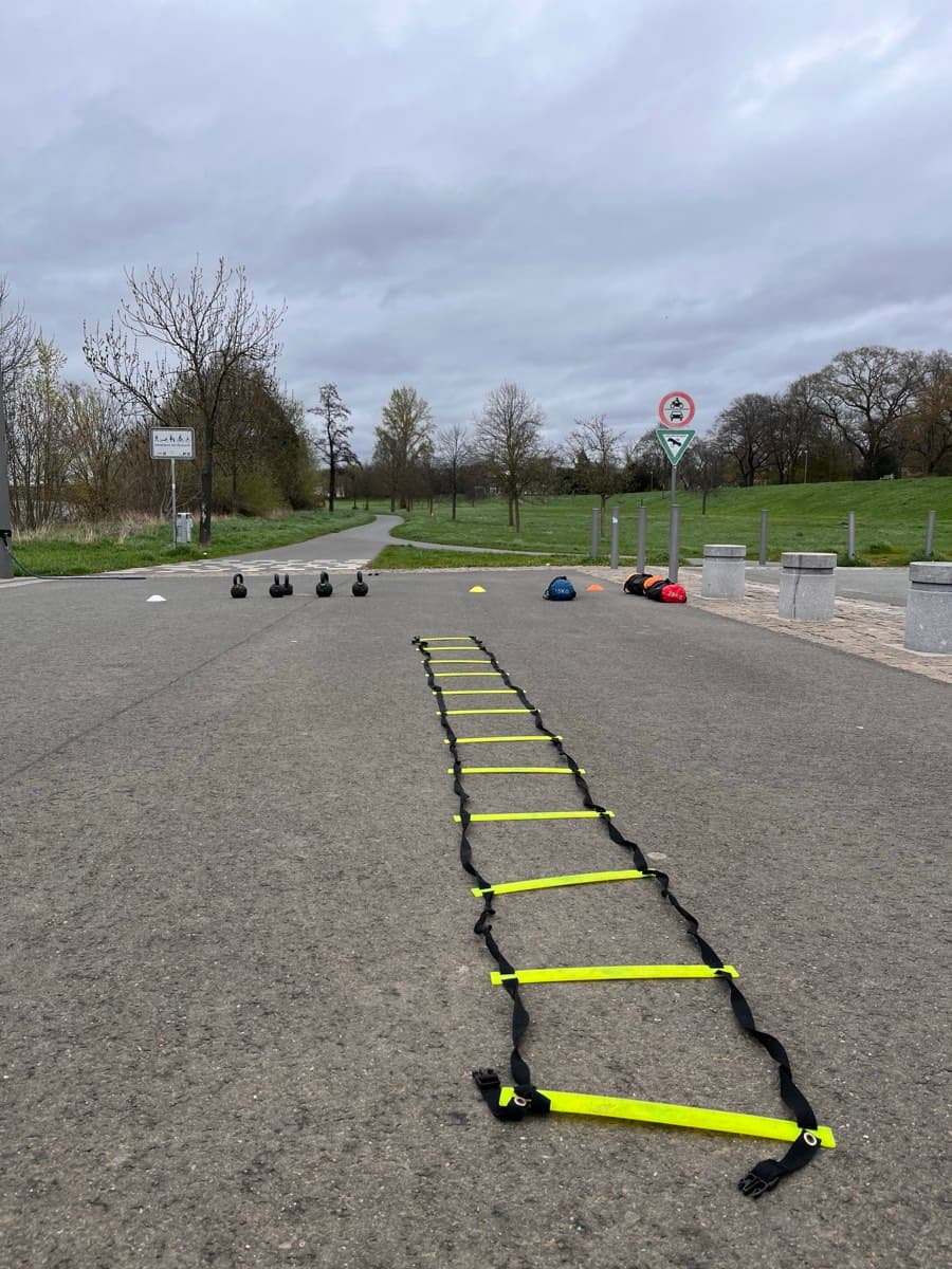 Outdoor corrective exercise setup with an agility ladder, kettlebells and markers