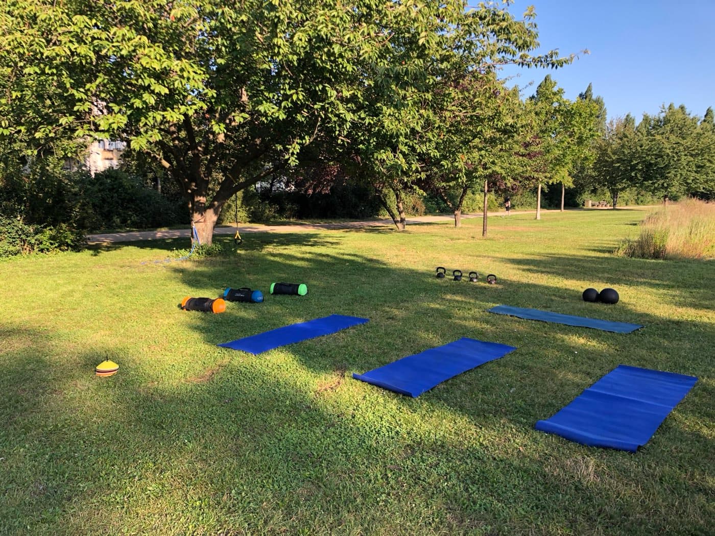 Outdoor training set-up — mats, kettlebells and sandbags ready in a coastal park